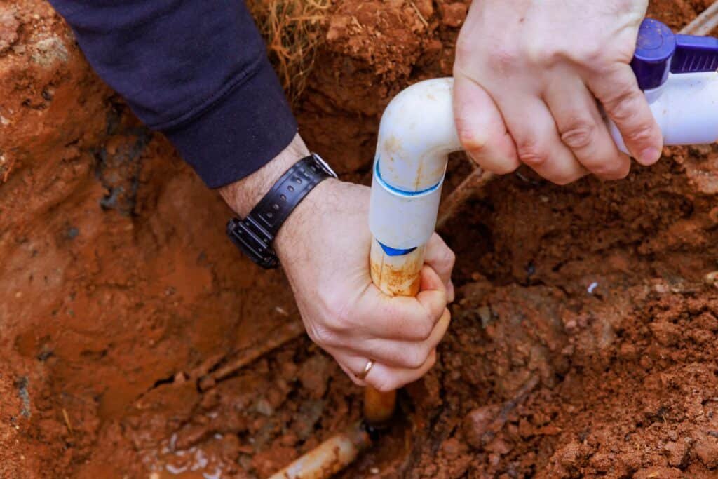 Plumber installing a PVC pipe to connect a house to the water supply